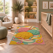 Yarn Balls and Knitting Needles Rug in a nursery with a crib and armchair