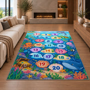 Blue ocean hopscotch rug with numbered bubbles, coral, fish and sea animals, styled beside a sofa
