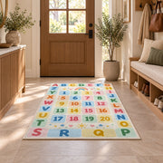 pastel alphabet number grid rug displayed in a entryway beside a wooden door