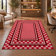 Red and Pink Checkered Border area rug in a study with an armchair and bookshelves