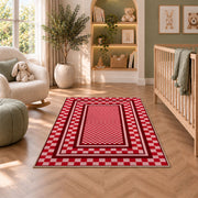 Red and Pink Checkered Border area rug in a nursery with a crib and armchair