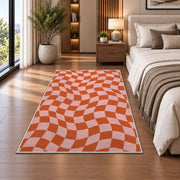 Wavy Orange and Pink Checkerboard area rug in a bedroom beside the bed