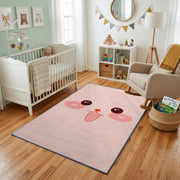 Pink Cute Face Area Rug — styled nursery room view