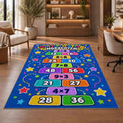 Multiplication Hopscotch Rug shown beside a lounge chair and wooden shelving