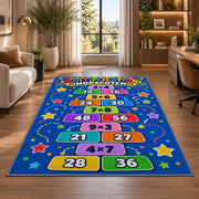 Multiplication Hopscotch Rug shown near large windows and a sofa