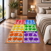 Rainbow Shapes Color Chart Rug shown beside a bed with neutral bedding