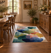 Pastel abstract pebble area rug in teal, navy, coral, yellow, and blush, front room mockup