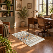 Cream and blue folk floral area rug with orange botanical details, complete product view