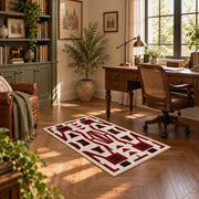 Burgundy and cream geometric area rug with a bold interlocking pattern, featured room view