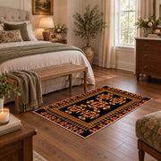 Black and orange tribal area rug with bold geometric border motifs, cozy home setting