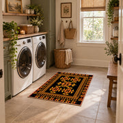 Black and orange tribal area rug with bold geometric border motifs, wide interior view
