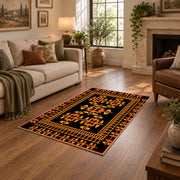 Black and orange tribal area rug with bold geometric border motifs, design detail view