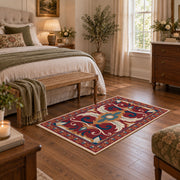 Red and blue ornate floral area rug with cream and teal scroll motifs, cozy home setting