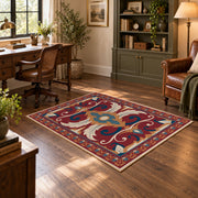 Red and blue ornate floral area rug with cream and teal scroll motifs, wood floor styling