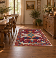 Red and blue ornate floral area rug with cream and teal scroll motifs, close decorative detail